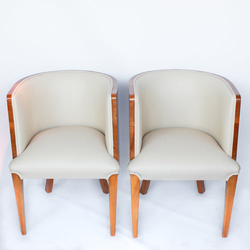 A pair of Art Deco tub chairs. Veneered walnut wrap frame. Solid satin birch legs. Upholstered in cream leather at Jeroen Markies.