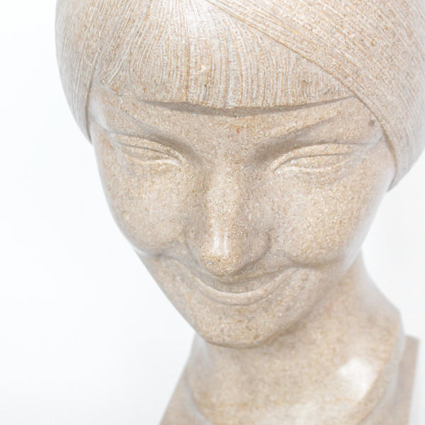 An Art Deco, stone carved sculpture of a smiling young lady, set over an integral plinth. Original dedication plaque to rear at Jeroen Markies.