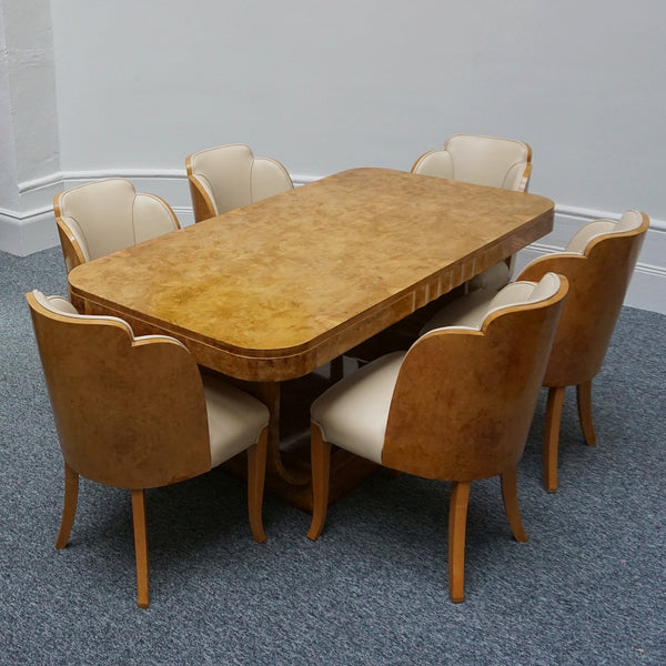 An Art Deco dining table with six chairs by Harry & Lou Epstein. The table top is burr walnut veneered. The six matching cloud backed armchairs are upholstered in cream leather