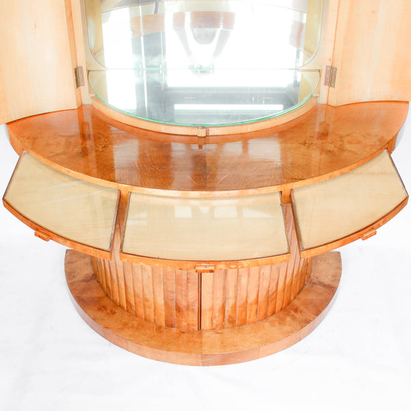 An Art Deco, demi-lune cocktail cabinet attributed to Harry & Lou Epstein. Mirrored, lit interior to top with glass shelves and mirrored slide tray. Lower, shelved cabinet with bottle holders. Burr walnut veneer at Jeroen Markies.