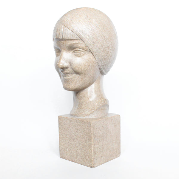 An Art Deco, stone carved sculpture of a smiling young lady, set over an integral plinth. Original dedication plaque to rear at Jeroen Markies.