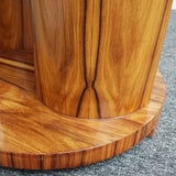 An Art Deco style centre table with a curved central column with hidden shelf to either side set over a circular base made from burr walnut veneer